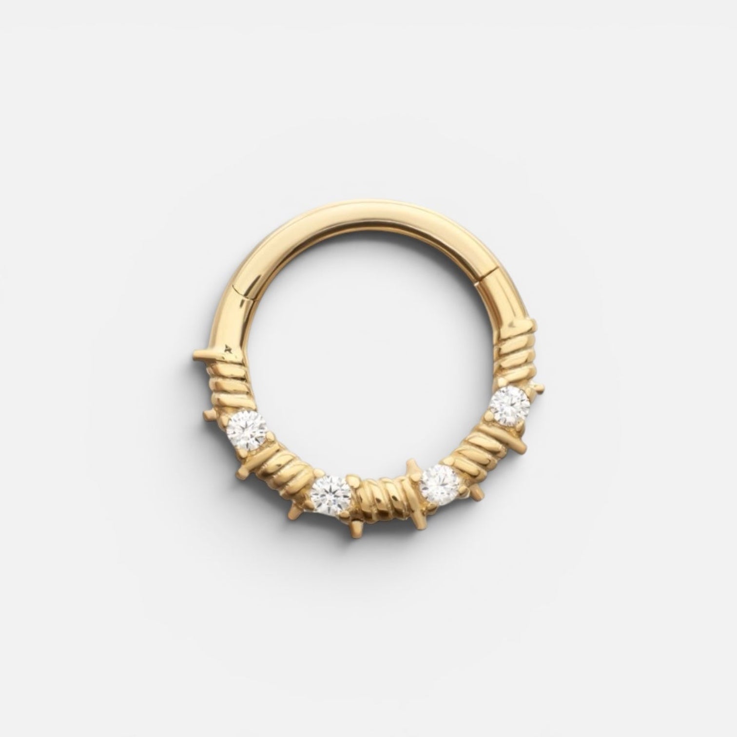Gold nose ring with embedded diamonds on a light gray background