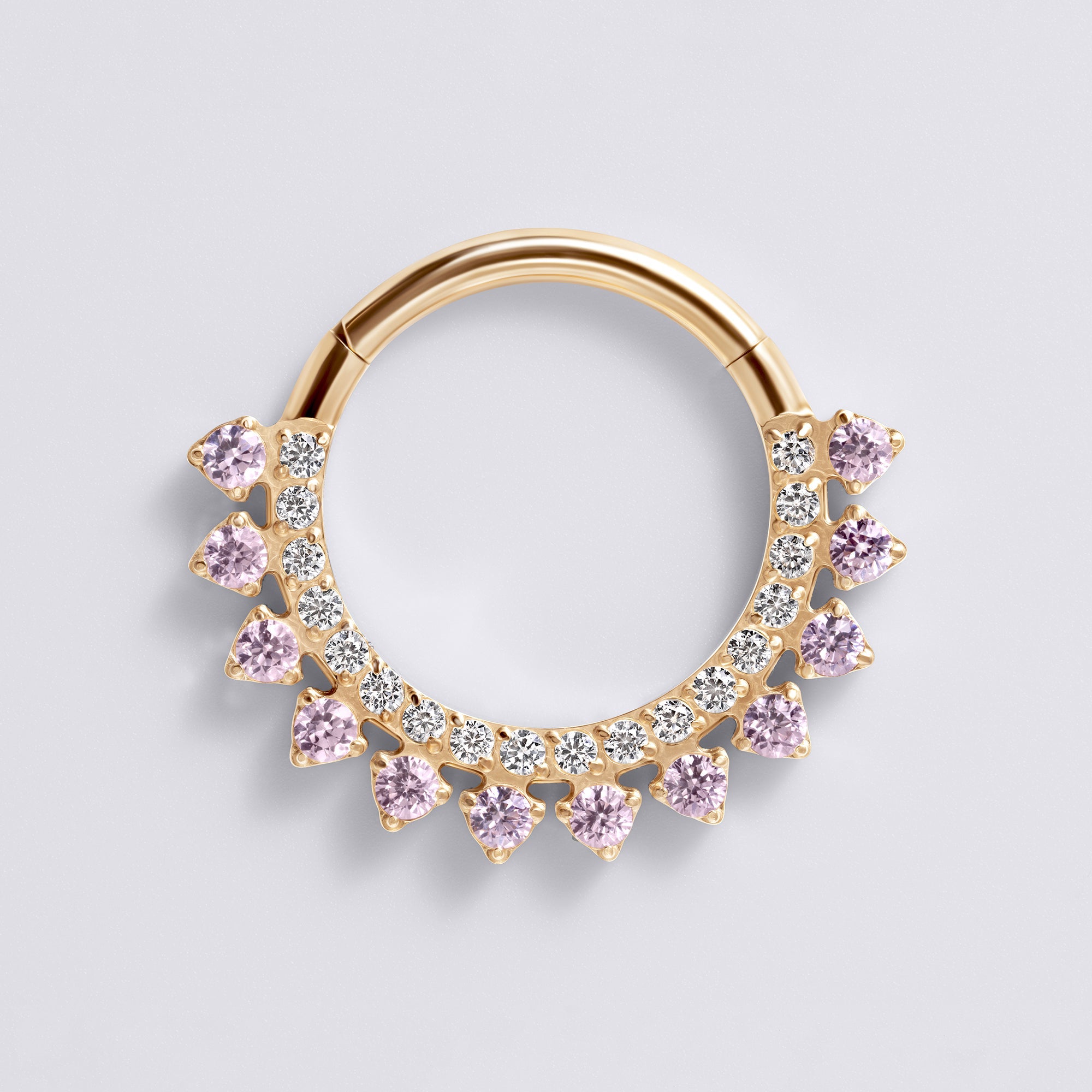 Gold nose ring with pink and clear gemstones on a light gray background